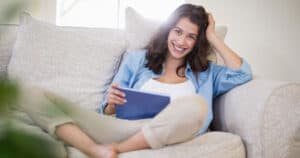 Woman Sitting on Couch with Tablet on Lap